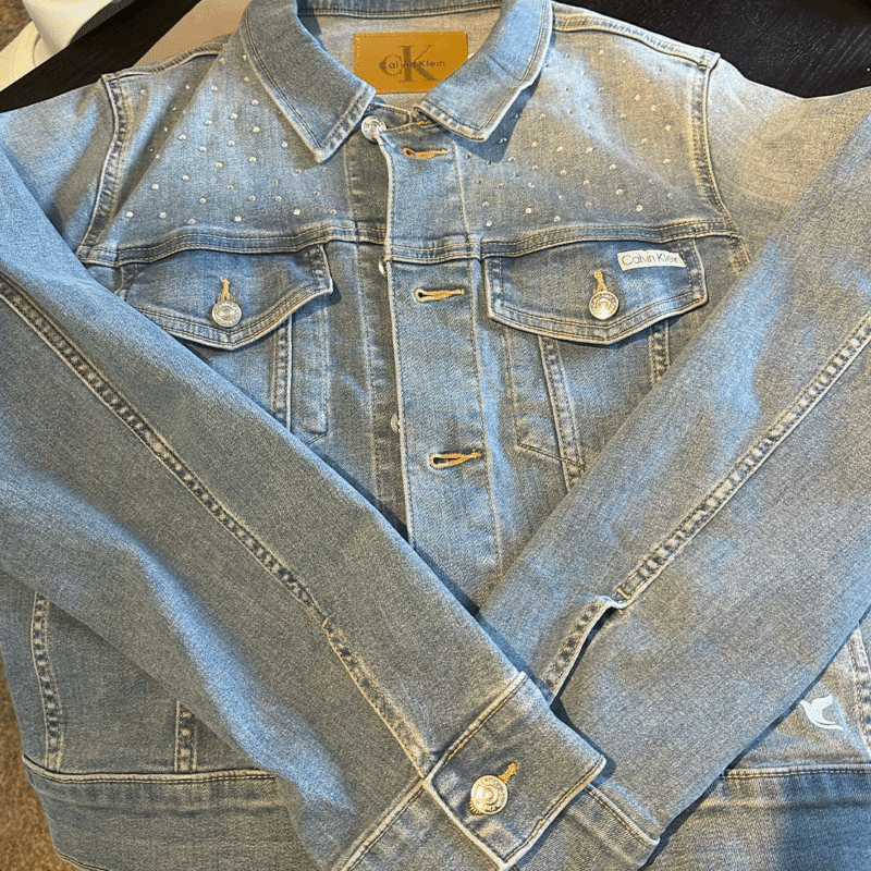 YAHWEH Denim Jacket Front Flat Lay Front of the Calvin Klein denim jacket with rhinestone details, button fastening and chest pockets