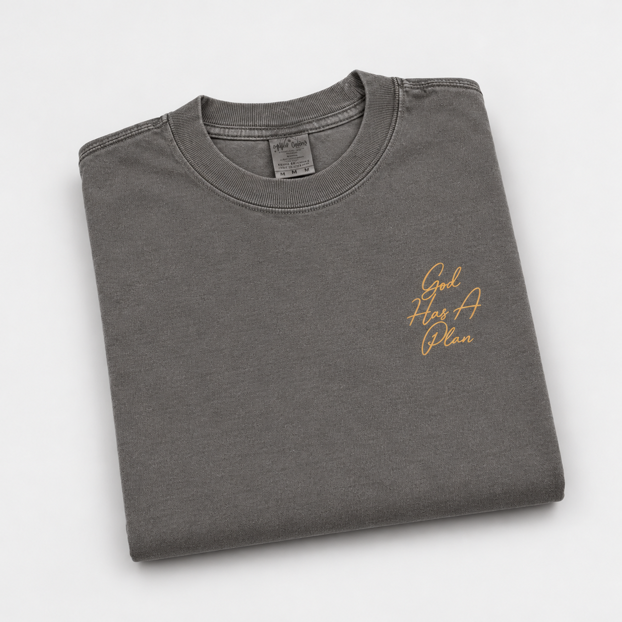 God Has a Plan oversized T-shirt in Shadow, folded with gold-colored script on the front